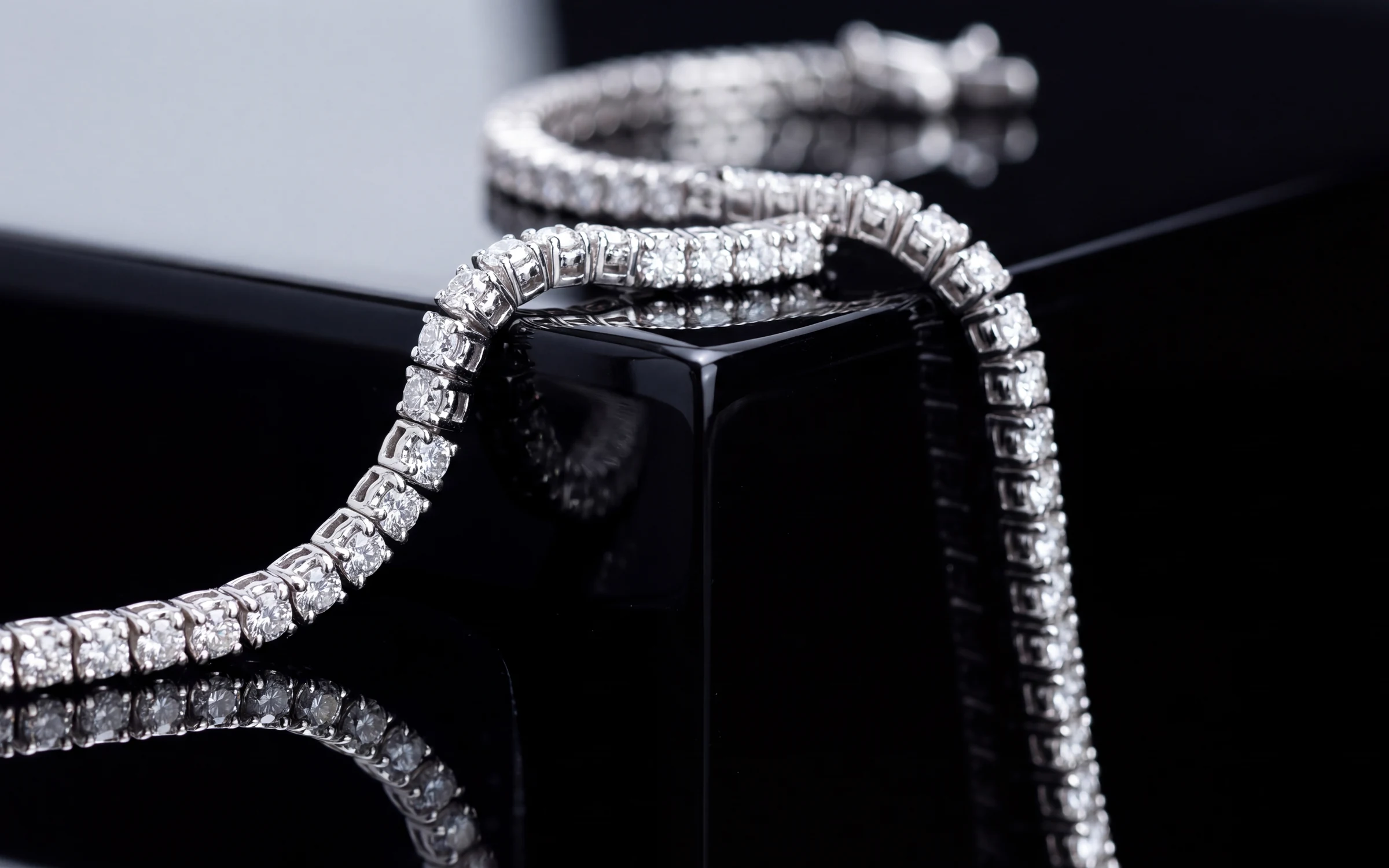 18K white gold diamond line bracelet draped over a black lacquer block, made with Aurix