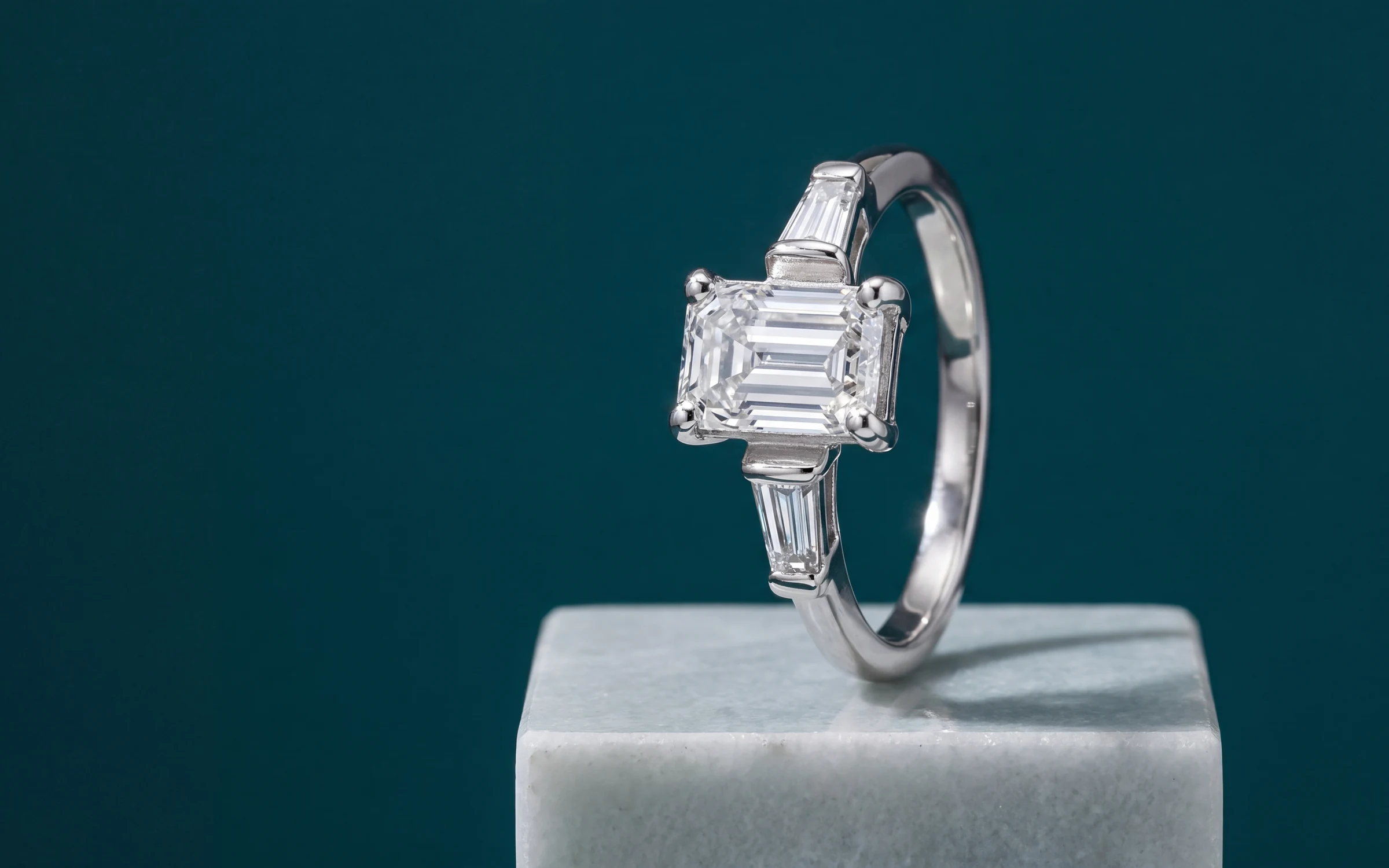 14K white gold emerald-cut diamond ring with tapered baguettes on a stone plinth, made with Aurix